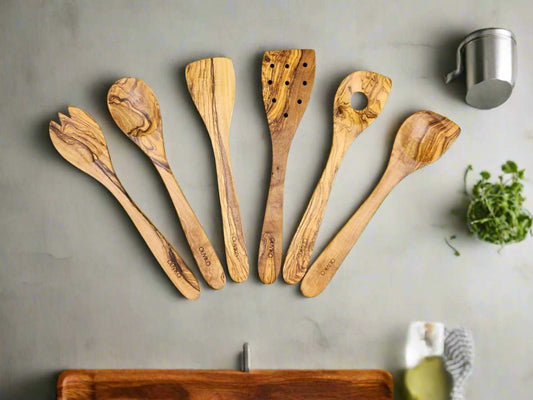 set of six handcrafted olive wood utensils with varied spoon and spatula designs on gray background