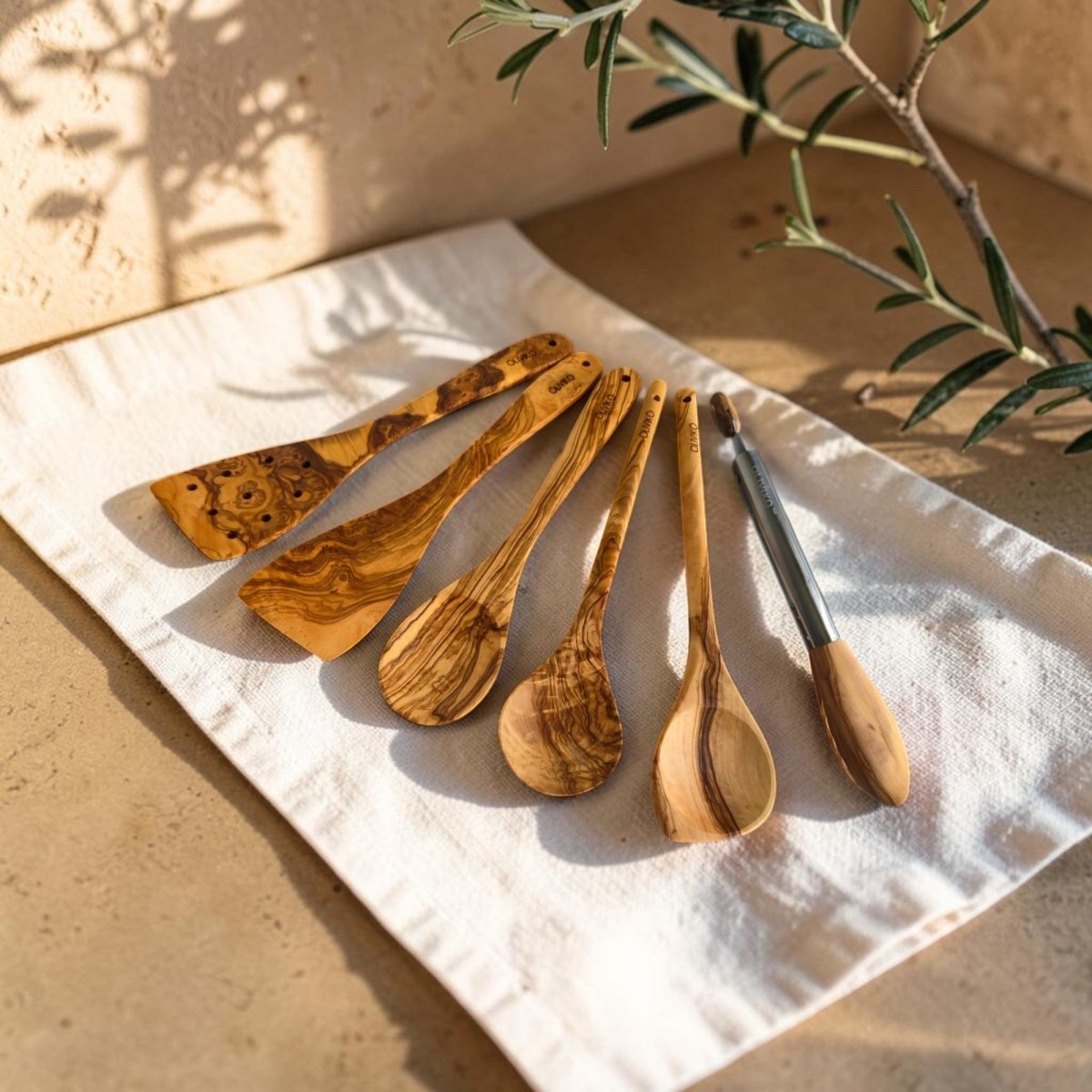 OLIVIKO Olive Wood Cooking Set – 6 Piece with Salad Tongs, lifestyle shot on kitchen cloth