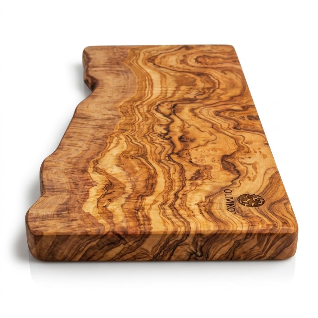 An olive wood cutting board with a natural irregular shape, featuring prominent wavy grain patterns in shades of golden brown and tan, with a visible 'OLYMPUS' logo on the bottom right corner, set against a plain white background.